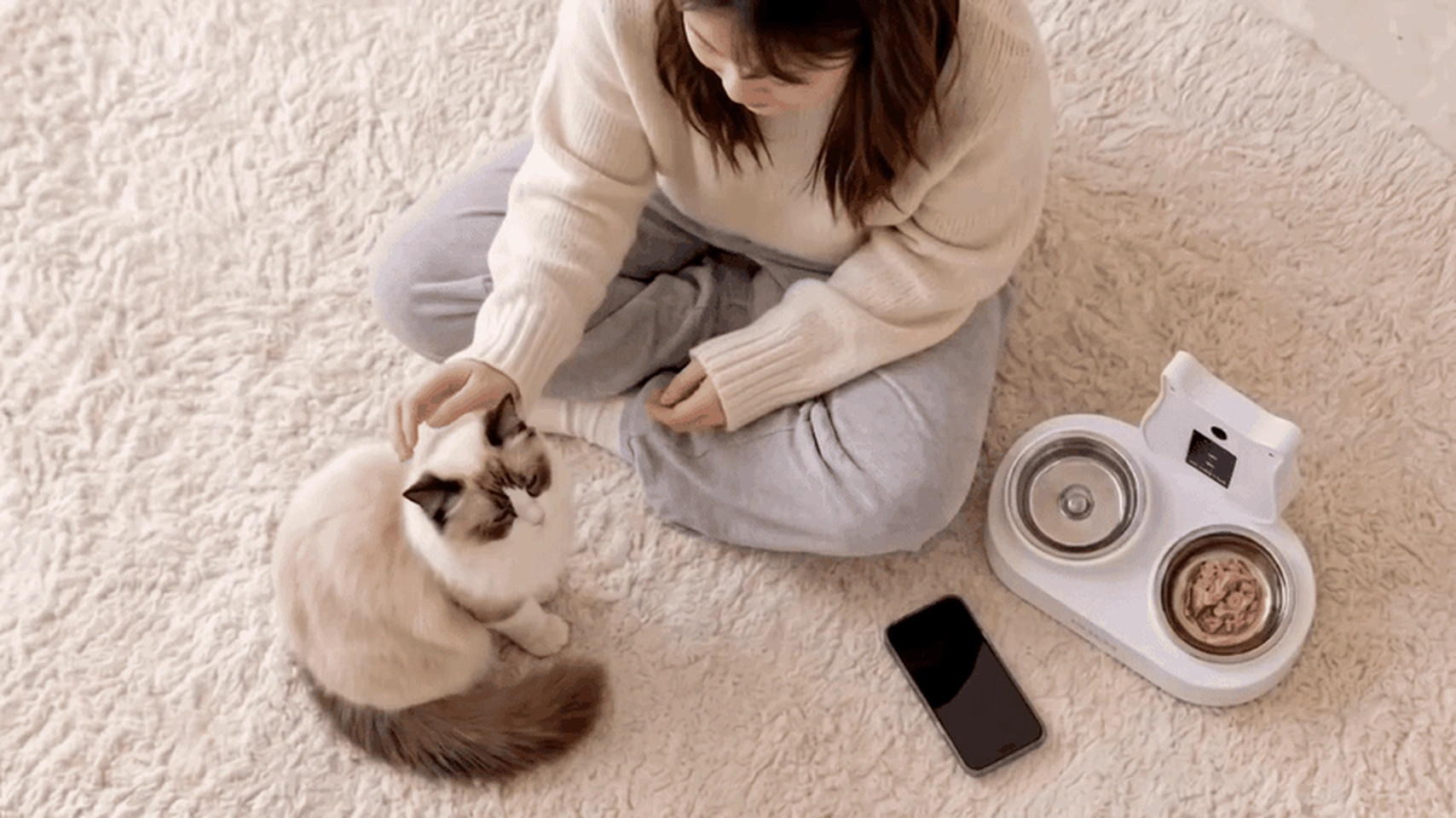 Una proprietaria seduta con il suo gatto accanto ad AI-Tails One a casa